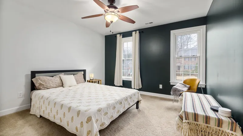 Bright bedroom with a made bed, ceiling fan and large windows