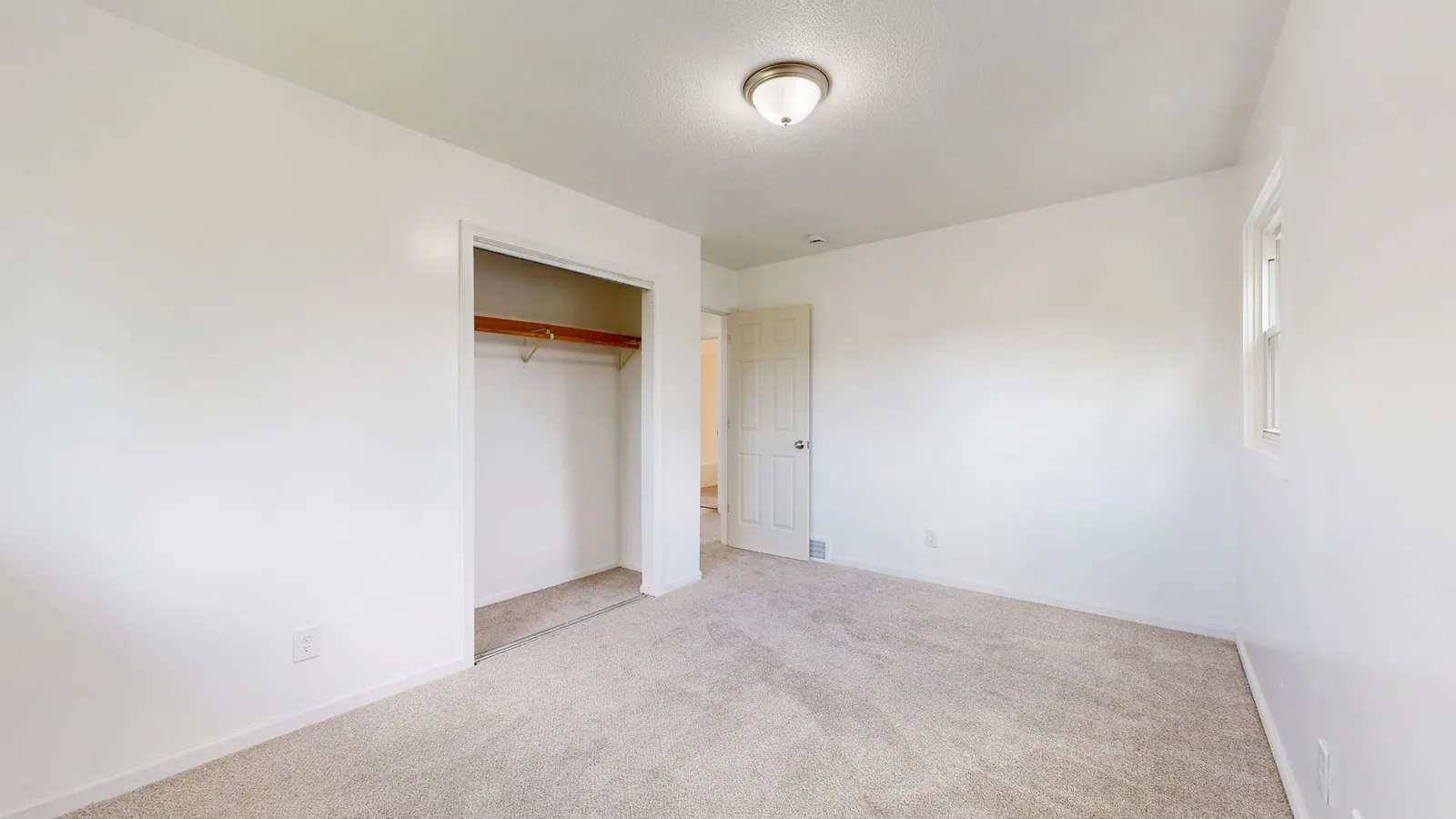 Empty bedroom with plush carpet and an open closet