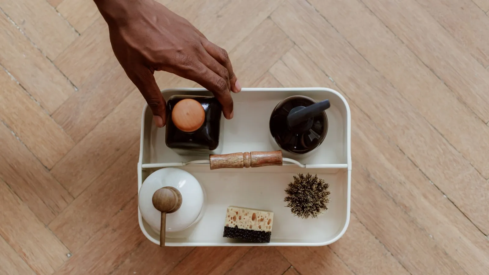 Top view of a cleaning kit with brush, sponge and bottles on a wood floor