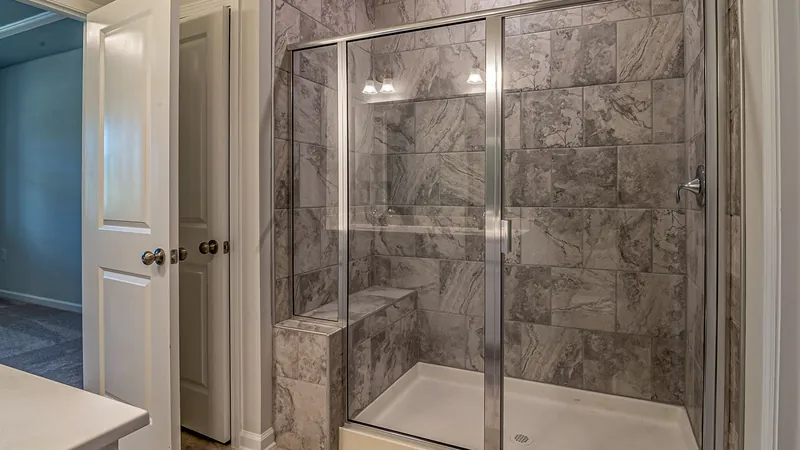 Bathroom with a marble-tiled shower behind glass doors