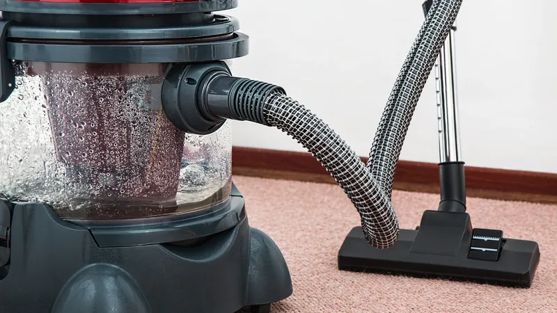 Canister vacuum cleaner standing on a carpeted floor