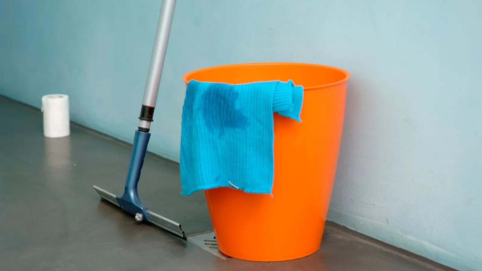 Orange bucket, mop and blue cloth on the floor