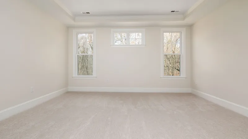 Empty carpeted room with three windows and natural light