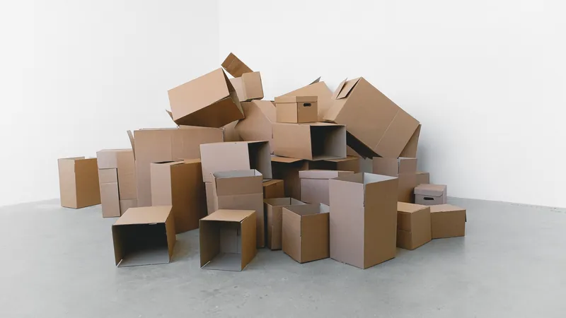 Pile of cardboard moving boxes against a white wall