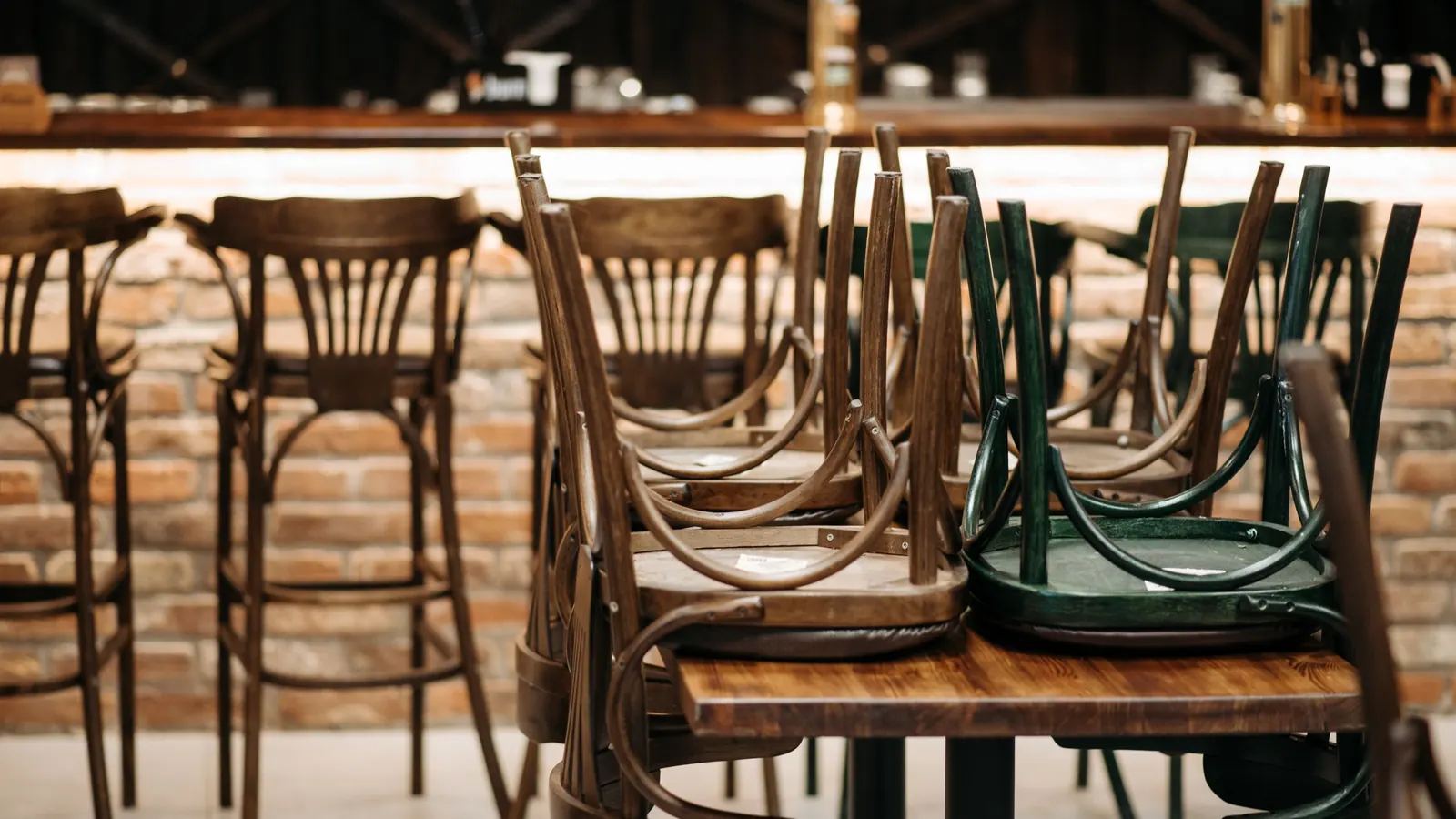 Wooden restaurant chairs turned upside down on tables after closing for floor cleaning