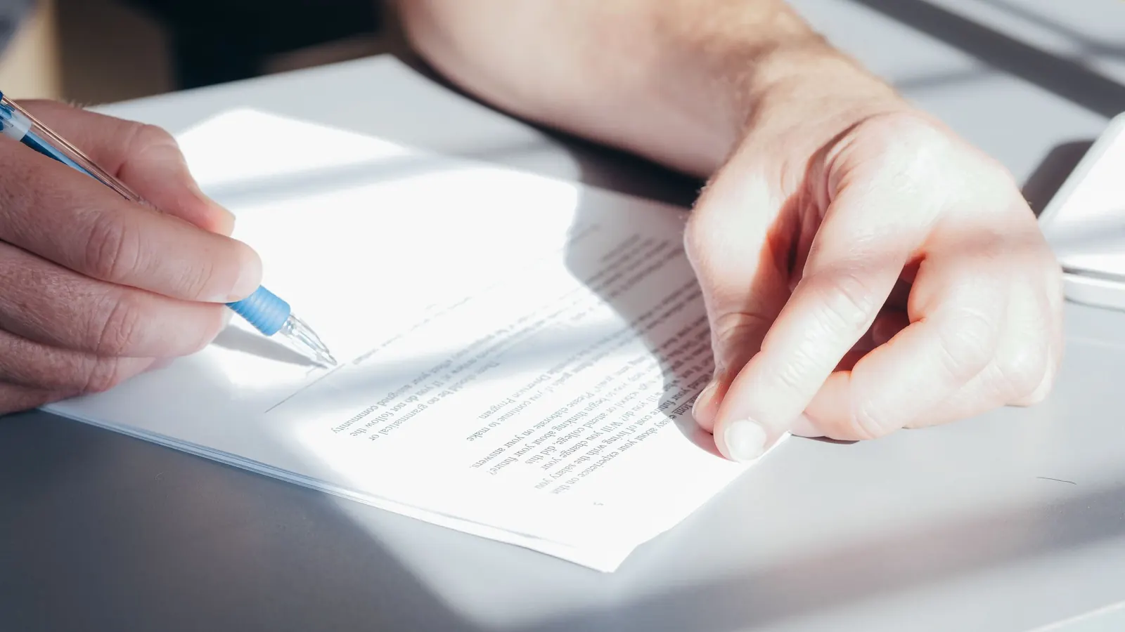 Hand signing a printed contract with a blue pen, as when an office changes cleaning vendors