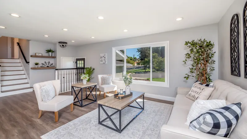 Tidy staged living room with a white sofa, coffee table, area rug and a large window
