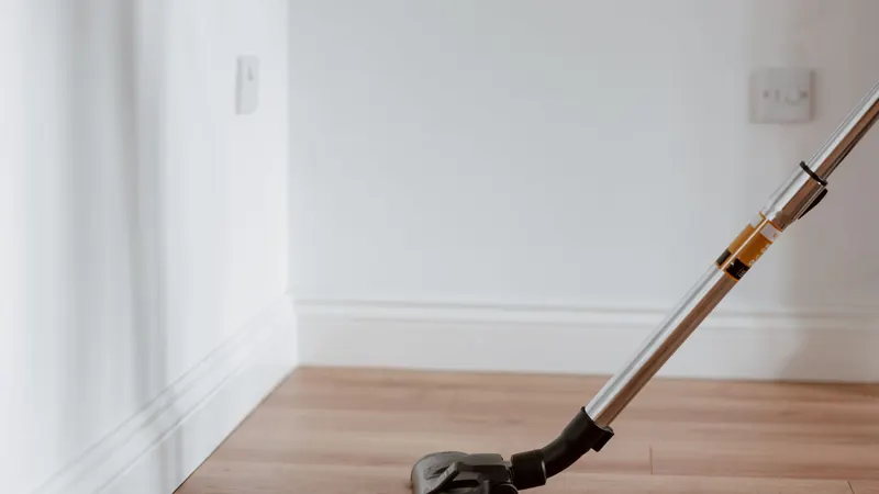 Vacuum floor head on a light hardwood floor along a white baseboard