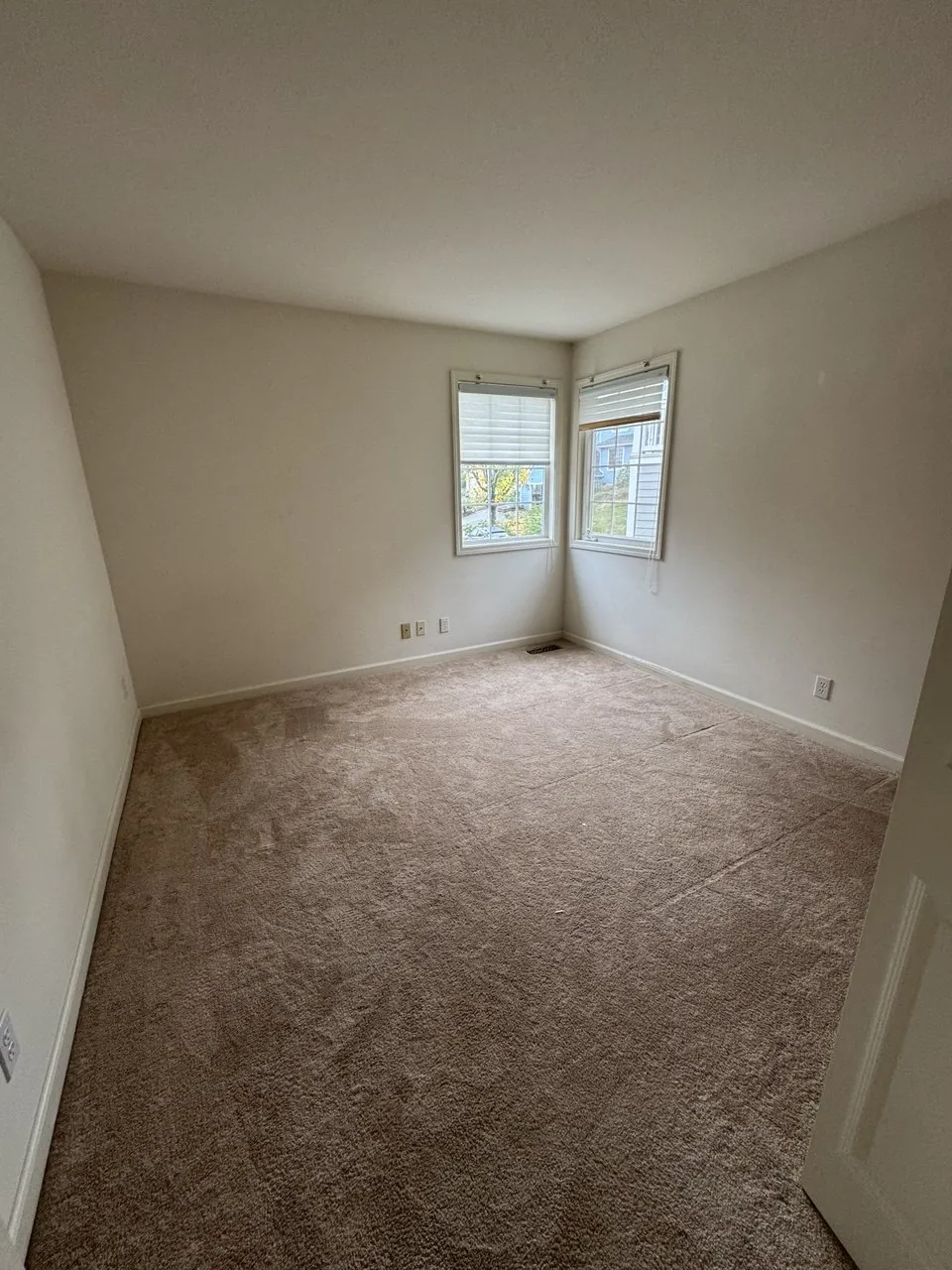 Before: empty bedroom carpet under corner windows