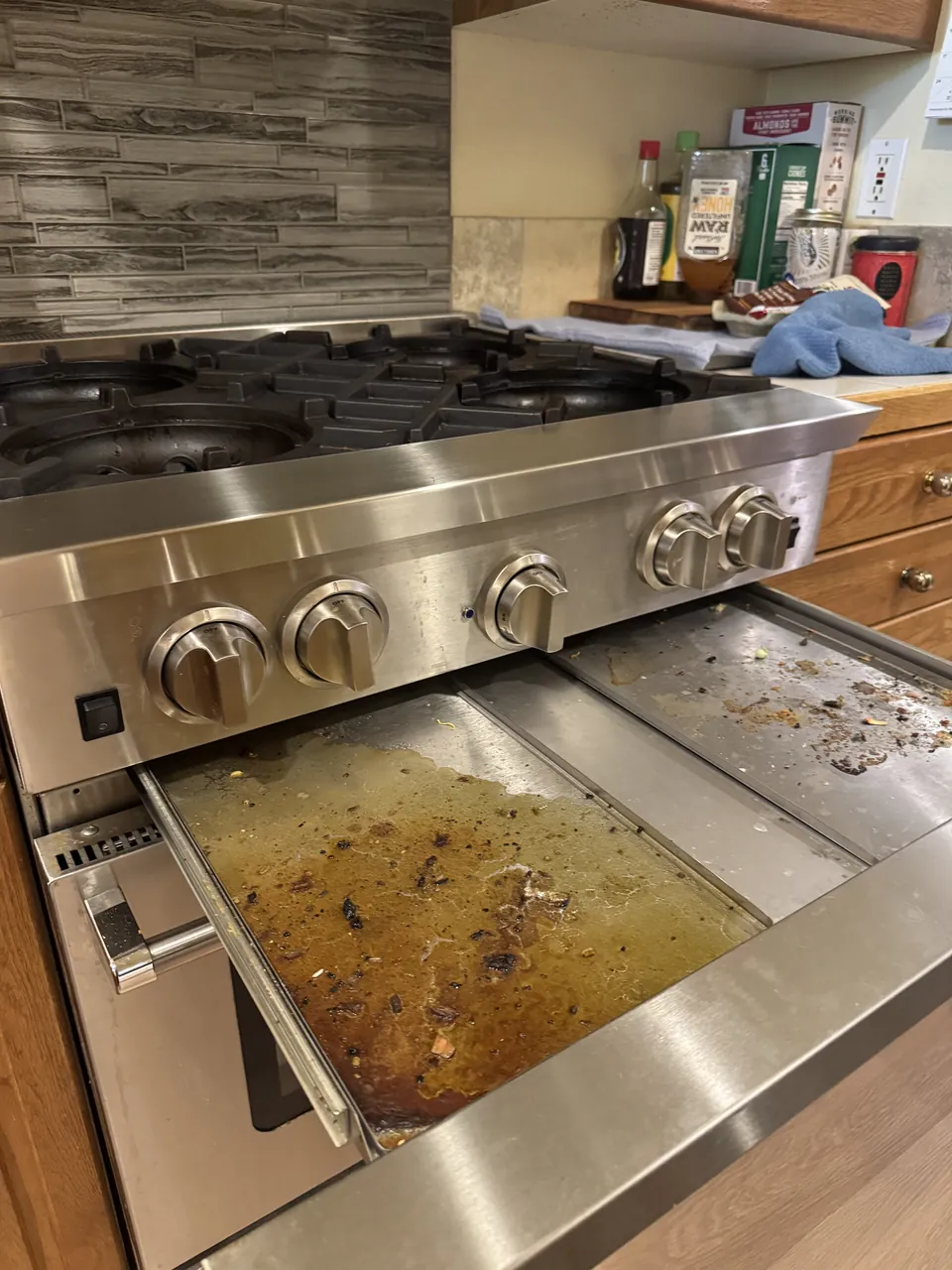 Before: professional range with grease-filled drip trays pulled out