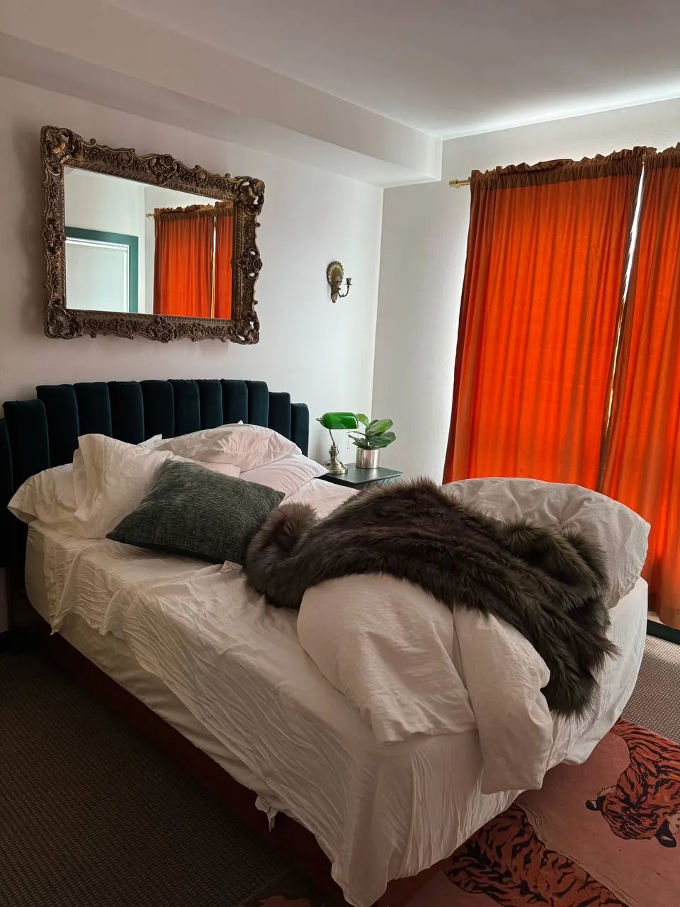 Before: bedroom with velvet headboard and orange curtains