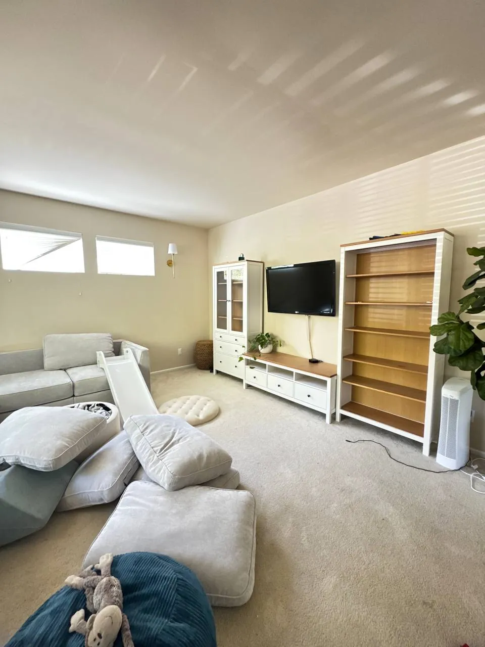 Before: family room TV wall and shelving, seen from the sofa side