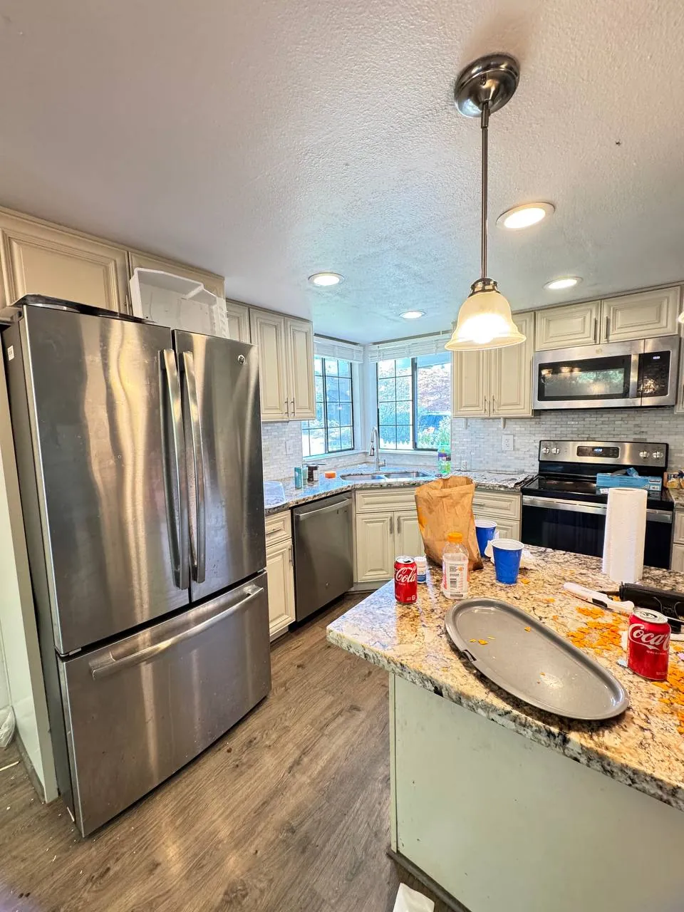 Before: kitchen with stainless fridge, granite island and cream cabinets