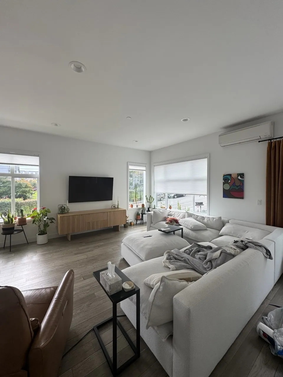 Before: bright living room with white sectional and wood floor