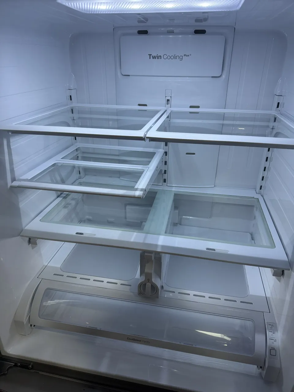 Empty refrigerator interior with glass shelves and drawers