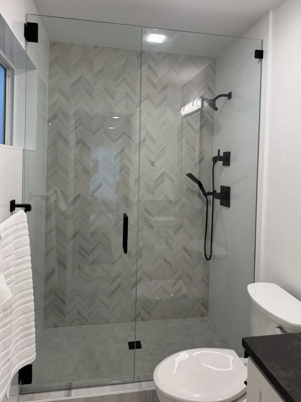 Shower with herringbone tile and frameless glass door
