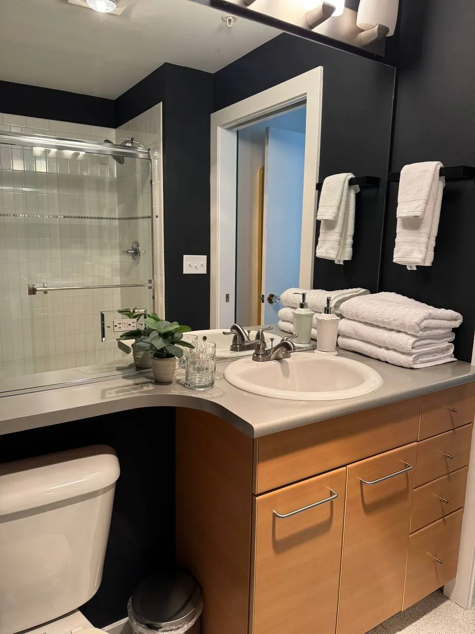 Bathroom vanity with wood cabinets, fresh towels and a dark accent wall