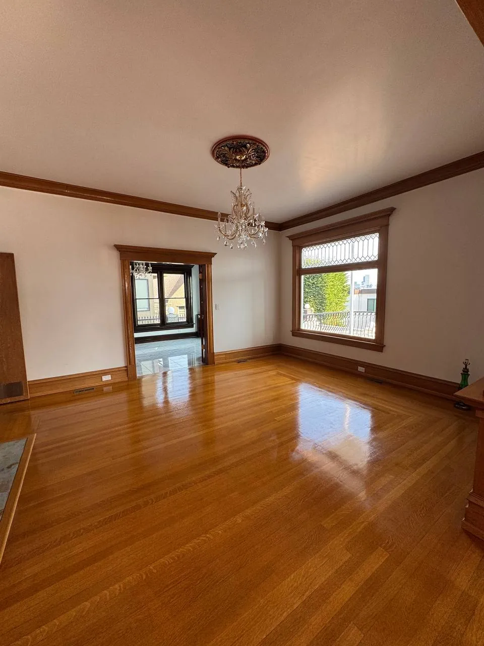 Empty living room with shining hardwood floor and chandelier