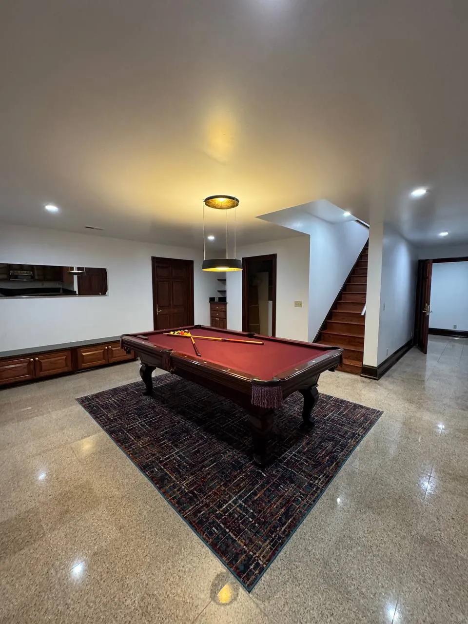 Game room with pool table on a rug over a polished floor