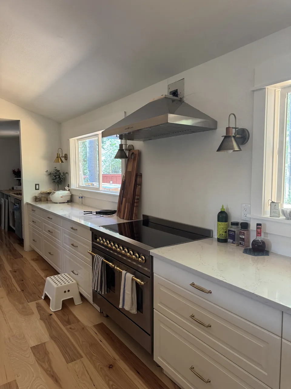 White kitchen with induction range, range hood and quartz counters