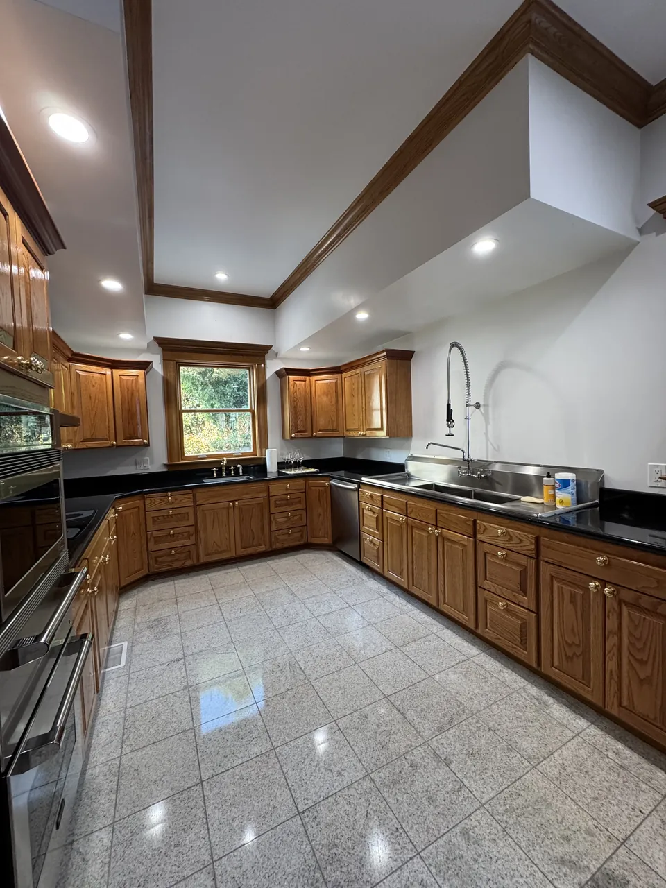 Large oak kitchen with black granite counters and polished tile floor