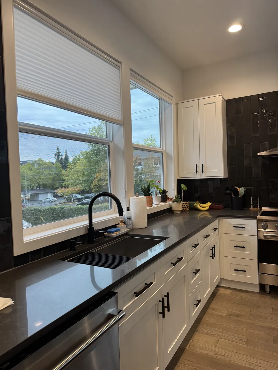 White kitchen with dark counters, black sink and tall windows