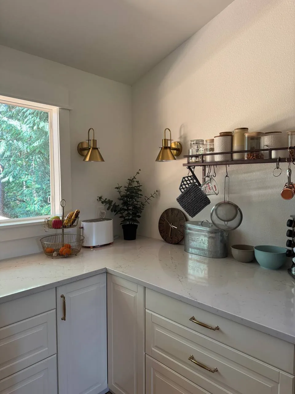 White kitchen corner with quartz counters and brass sconces