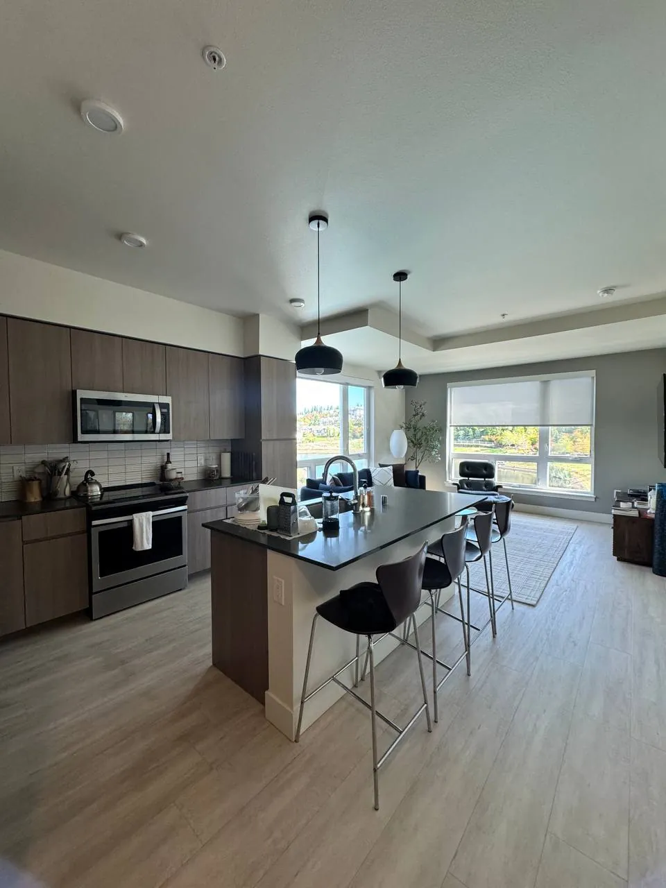 Open kitchen with dark island, stools and vinyl plank floor