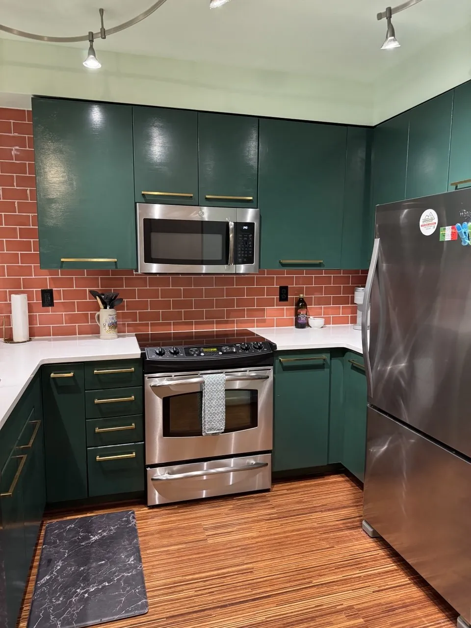 Kitchen with green cabinets, red tile backsplash and stainless range