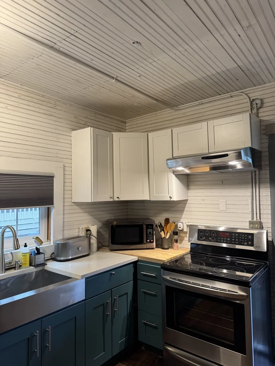 Kitchen with white upper cabinets, teal lowers and electric range
