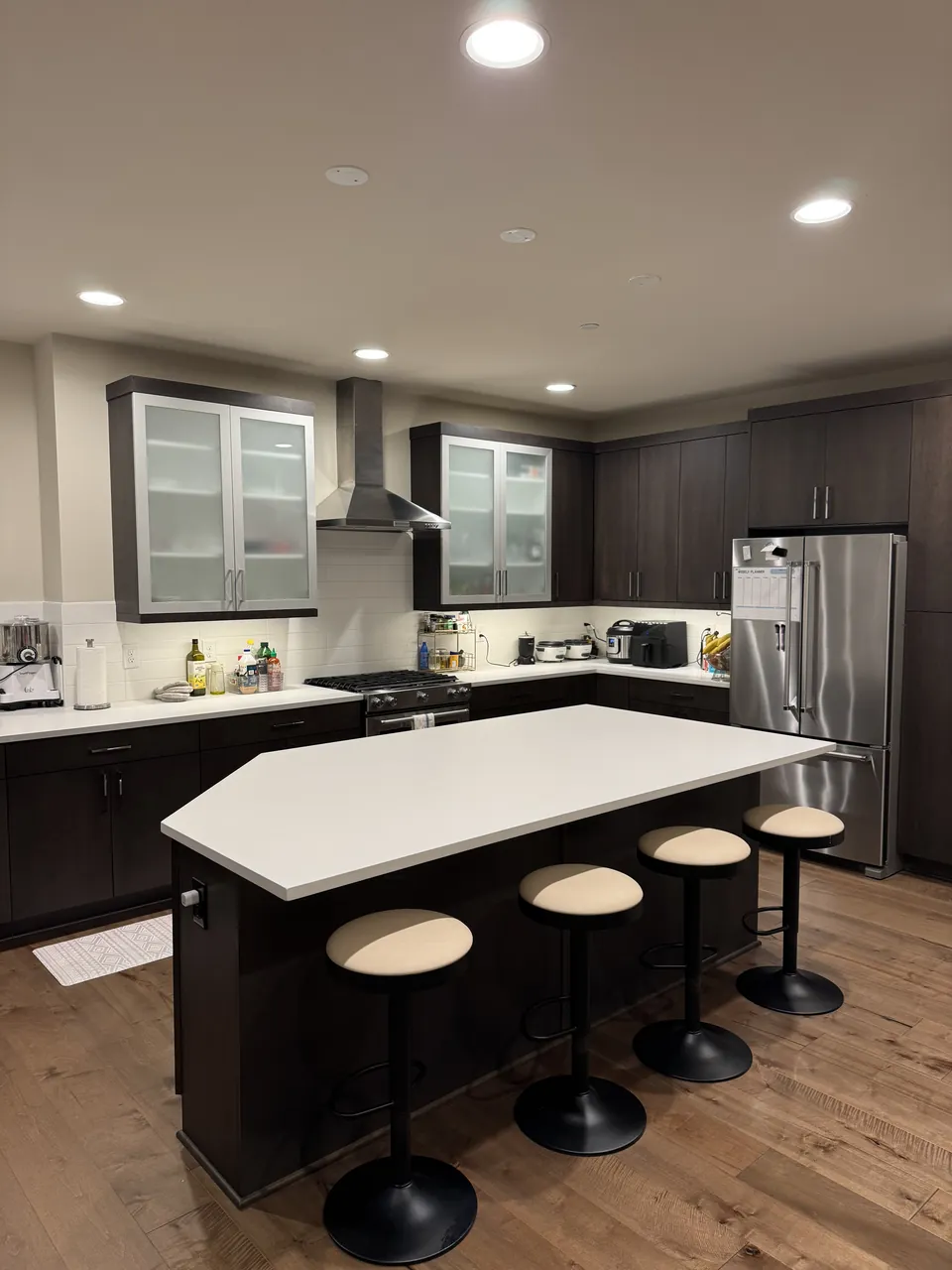 Dark wood kitchen with a white island and four stools