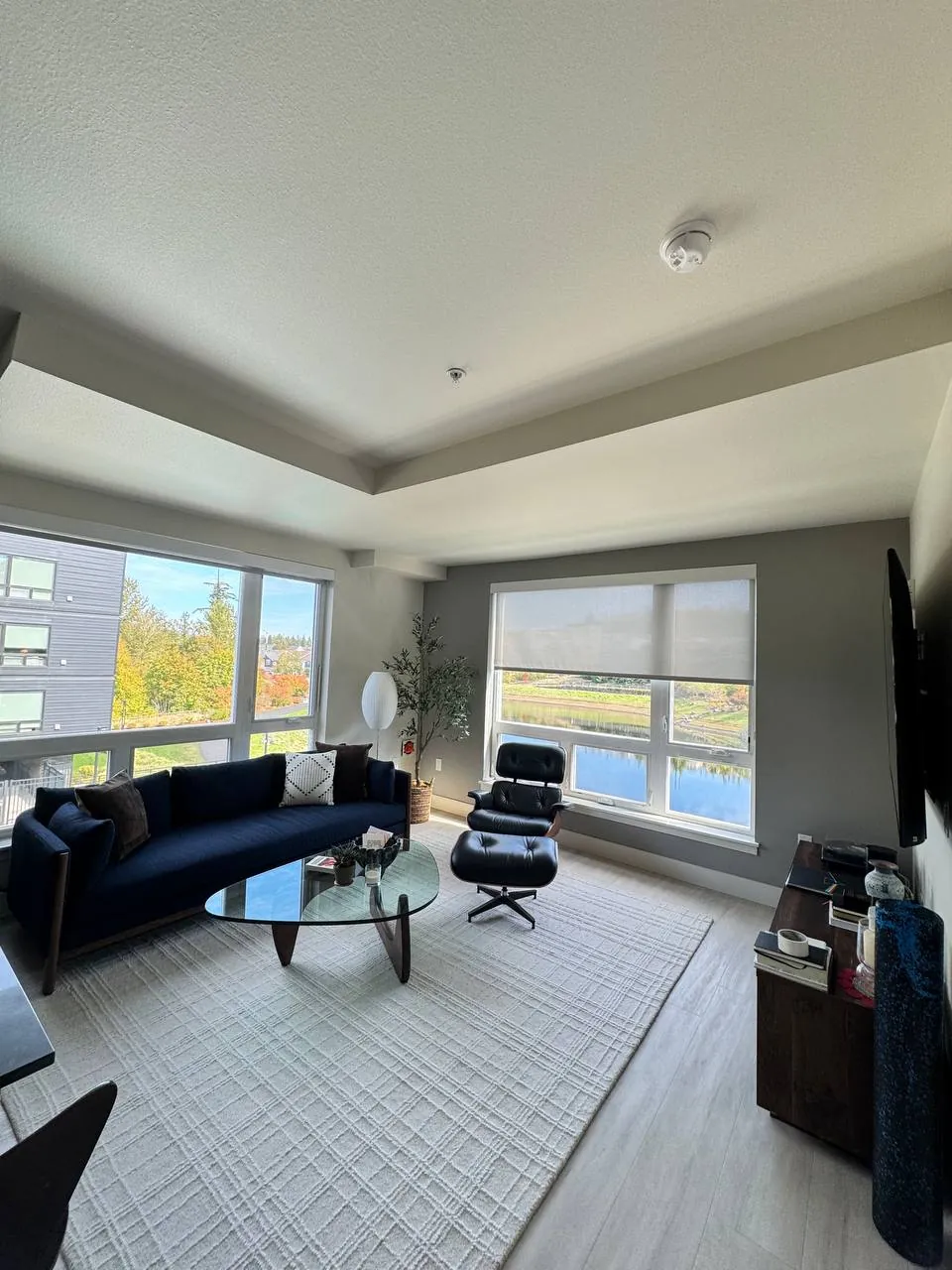 Living room with navy sofa, glass coffee table and large windows