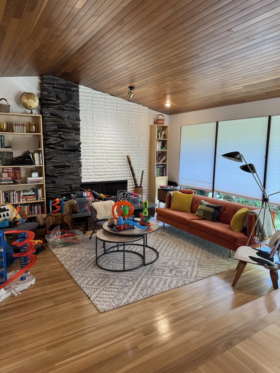 Living room with wood ceiling, stone fireplace wall and orange sofa