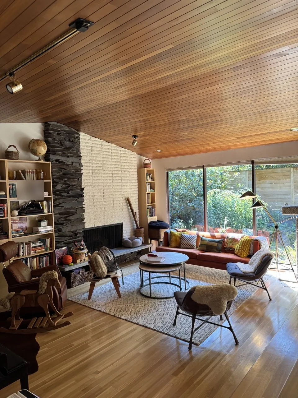 Living room with wood ceiling, bookshelves and a garden window