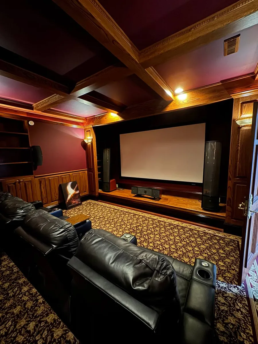Home theater with leather recliners, wood-paneled walls and patterned carpet