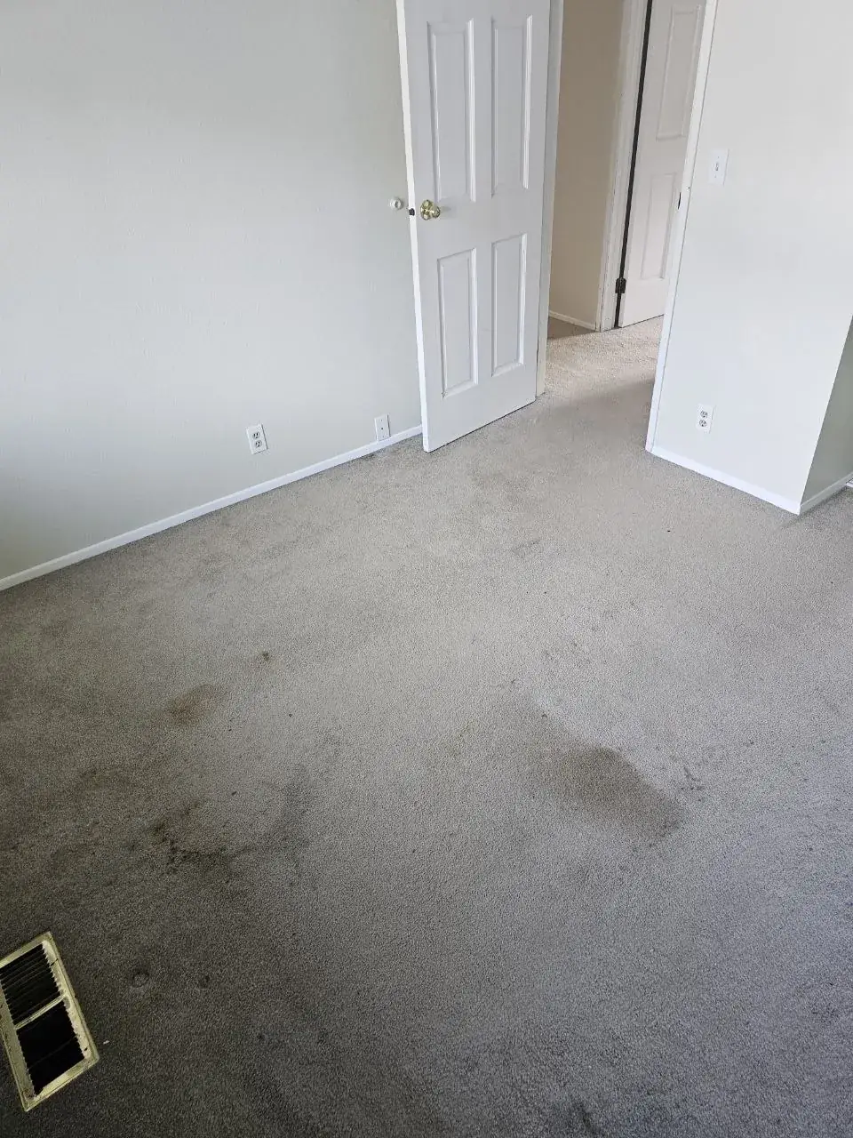 Before: vacant rental bedroom carpet with spots by the door